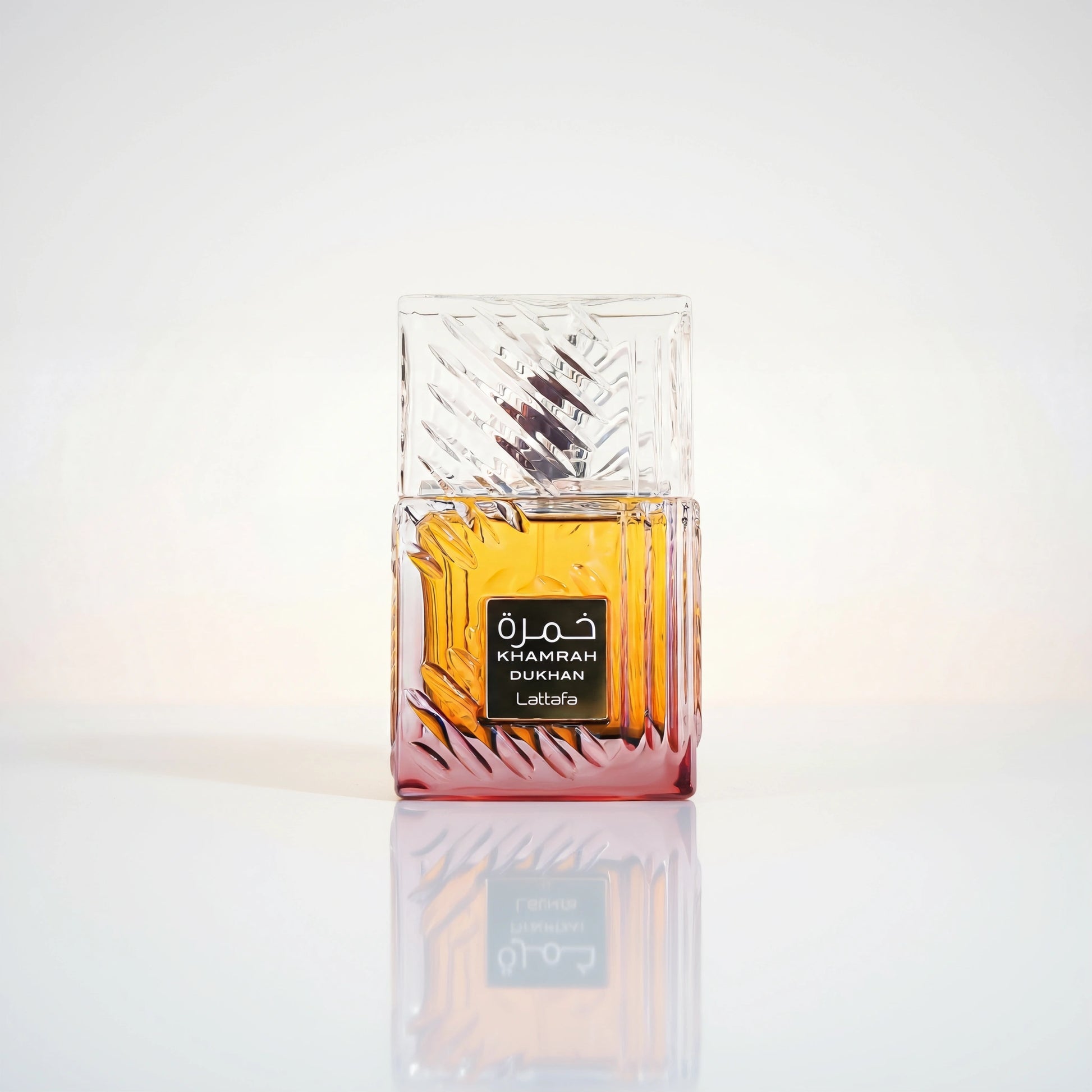 Lattafa Khamrah Dukhan Eau de Parfum Flakon aus geschliffenem Glas mit bernsteinfarbener Flüssigkeit und Spiegelung.
