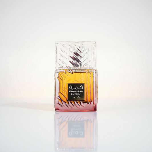 Lattafa Khamrah Dukhan Eau de Parfum Flakon aus geschliffenem Glas mit bernsteinfarbener Flüssigkeit und Spiegelung.