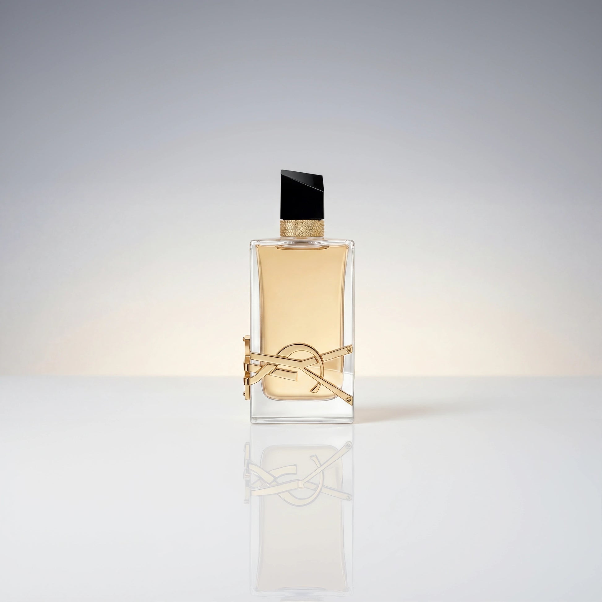 Eleganter Flakon des Yves Saint Laurent Libre Eau de Parfum mit goldener Logo-Verzierung und Spiegelung auf hellem Untergrund.